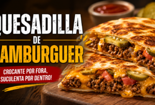 Quesadilla de hambúrguer recheada com carne moída, queijo derretido e picles, dourada e crocante, servida sobre tábua de madeira.
